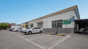 Ein Parkplatz mit mehreren weißen Autos, einer Ladestation und einem Gebäude, das freie Parkplätze anzeigt.