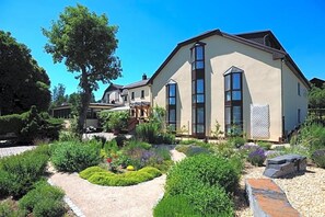 Una casa moderna con jardín, camino de entrada pavimentado y un gran árbol.