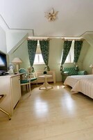 Una habitación con cama, escritorio, silla, una mesita y un radiador.