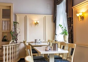 Un comedor con mesas y sillas, una planta en maceta e iluminación en la pared.