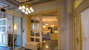 Um saguão de hotel com balcão de recepção, área de estar e porta de vidro que dá para uma sala de jantar.