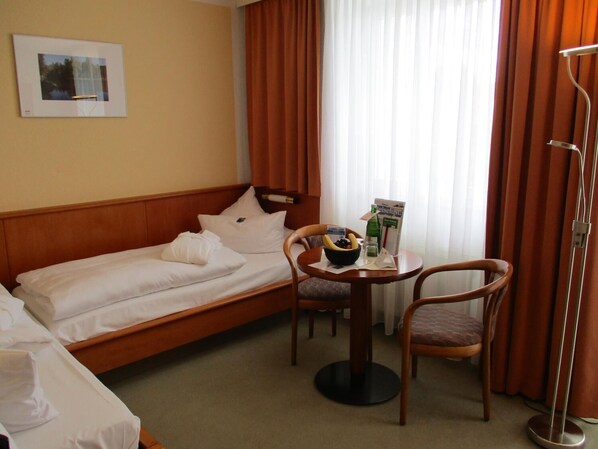 Una habitación de hotel con una cama, una mesita con un frutero y una silla.