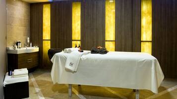 Un spa moderno con una camilla de masaje, un lavabo y un pequeño rincón de descanso.
