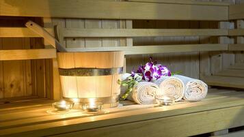 A wooden sauna bench with a wooden bucket and rolled towels.
