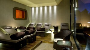 Un cuarto de spa con sillones reclinables, una camilla de masaje y un ventanal con vistas.