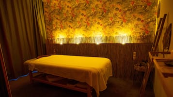 A room with a bed, a wooden headboard, and a wall with a floral pattern.