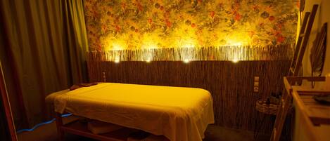 A room with a bed, a wooden headboard, and a wall with a floral pattern.