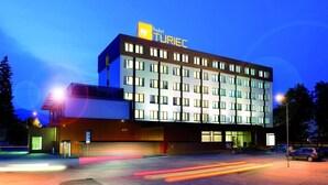 Un edificio moderno de hotel con un letrero llamativo, varios pisos y un área de estacionamiento.