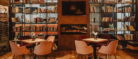 Una biblioteca acogedora con estanterías, chimenea y asientos cómodos.