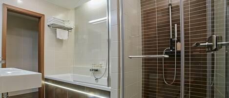 Un baño moderno con ducha acristalada, lavabo blanco y mampara de vidrio.
