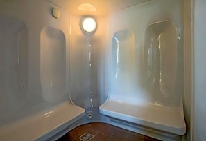 A corner of a bathroom with two white bathtubs, a round mirror, and a light fixture on the ceiling. - Hotel Adler (Ingolstadt)