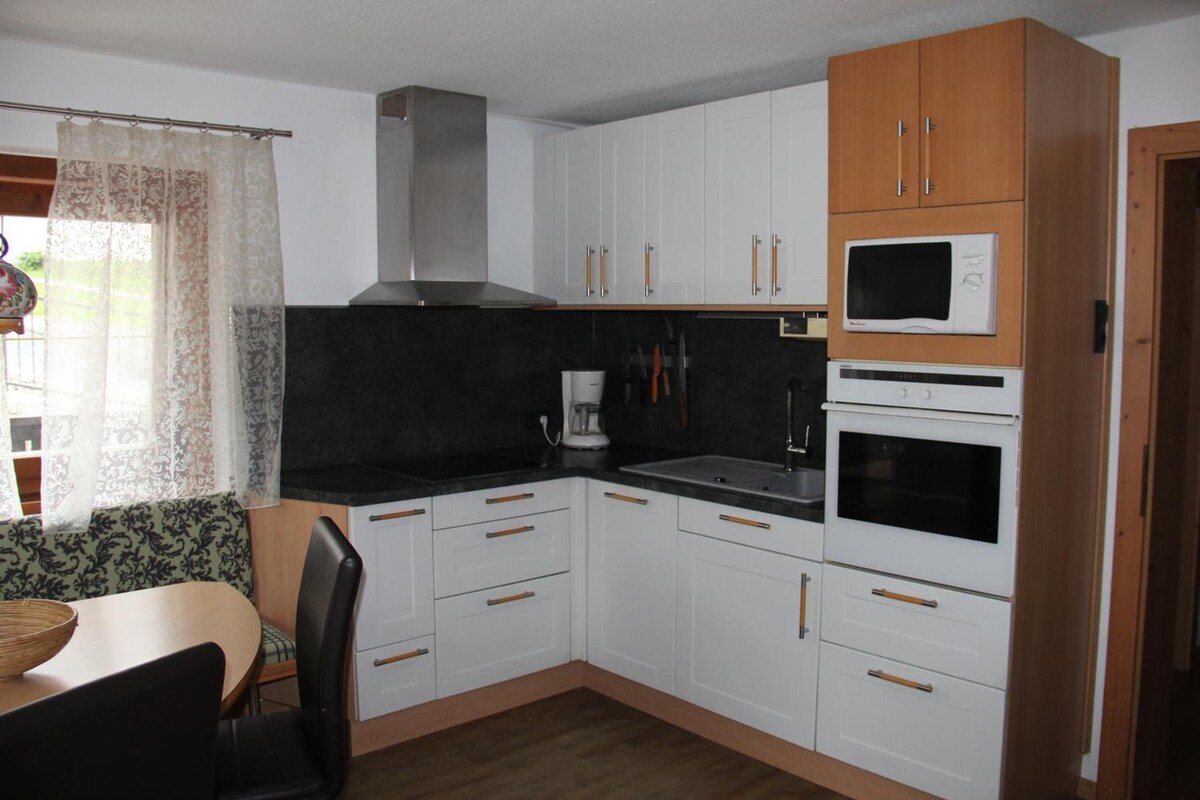 A compact kitchen with white cabinets, a microwave, an oven, and a coffee maker.