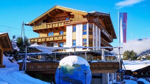 A hotel with a wooden facade, multiple balconies, and a large globe in the foreground. - Hotel Schweizerhof (Wildschönau)