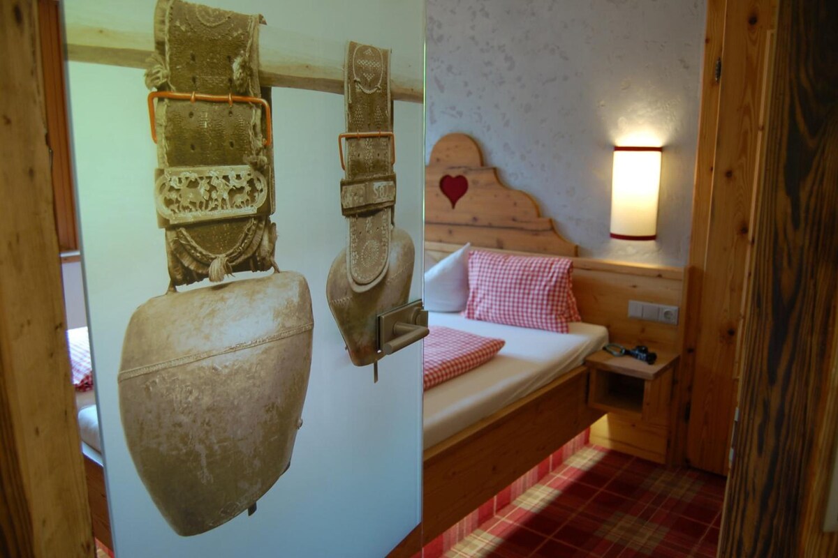 Ein rustikaler Raum mit einem hölzernen Bett, einer Wandlampe und einem großen Dekoartikel.