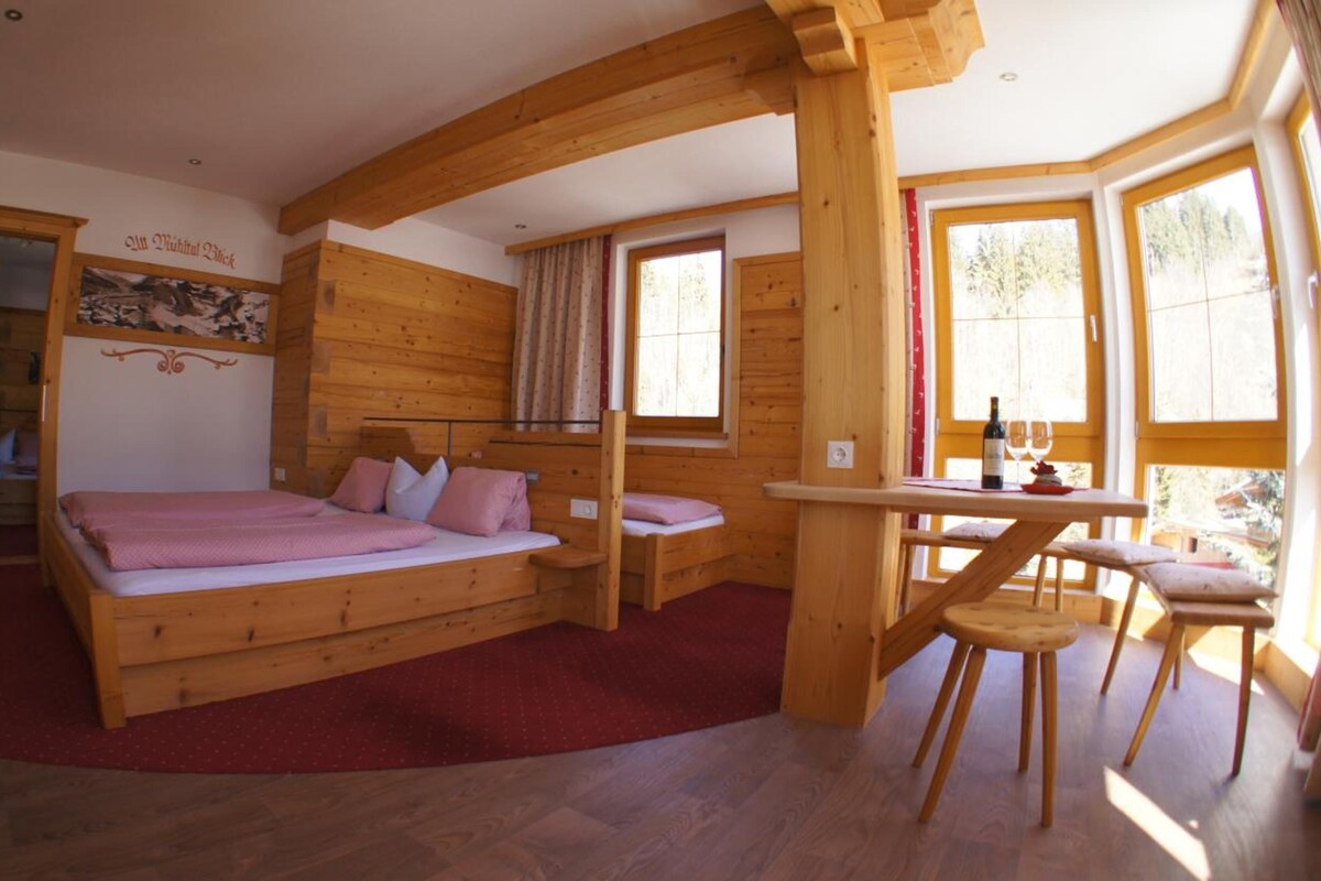 A wooden cabin with a bed, a table with chairs, and a window.