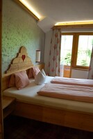 Un dormitorio con cama de madera, cabecera con recorte en forma de corazón y ventana con cortinas.