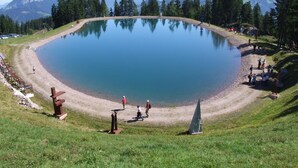 A large circular lake surrounded by a grassy area with a few people walking around. - Hotel Schweizerhof (Wildschönau)