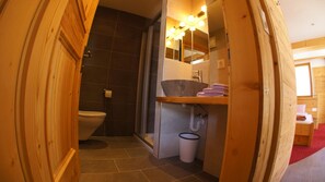 A bathroom with a toilet, a sink with a basin, a mirror with lights, and a towel rack.
