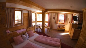 Une cabane en bois comprenant deux lits, une table à manger et un téléviseur.