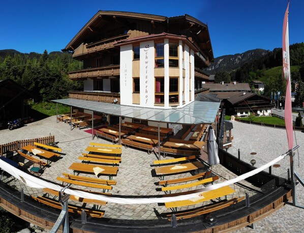 A traditional wooden building with a covered outdoor seating area and a flagpole.