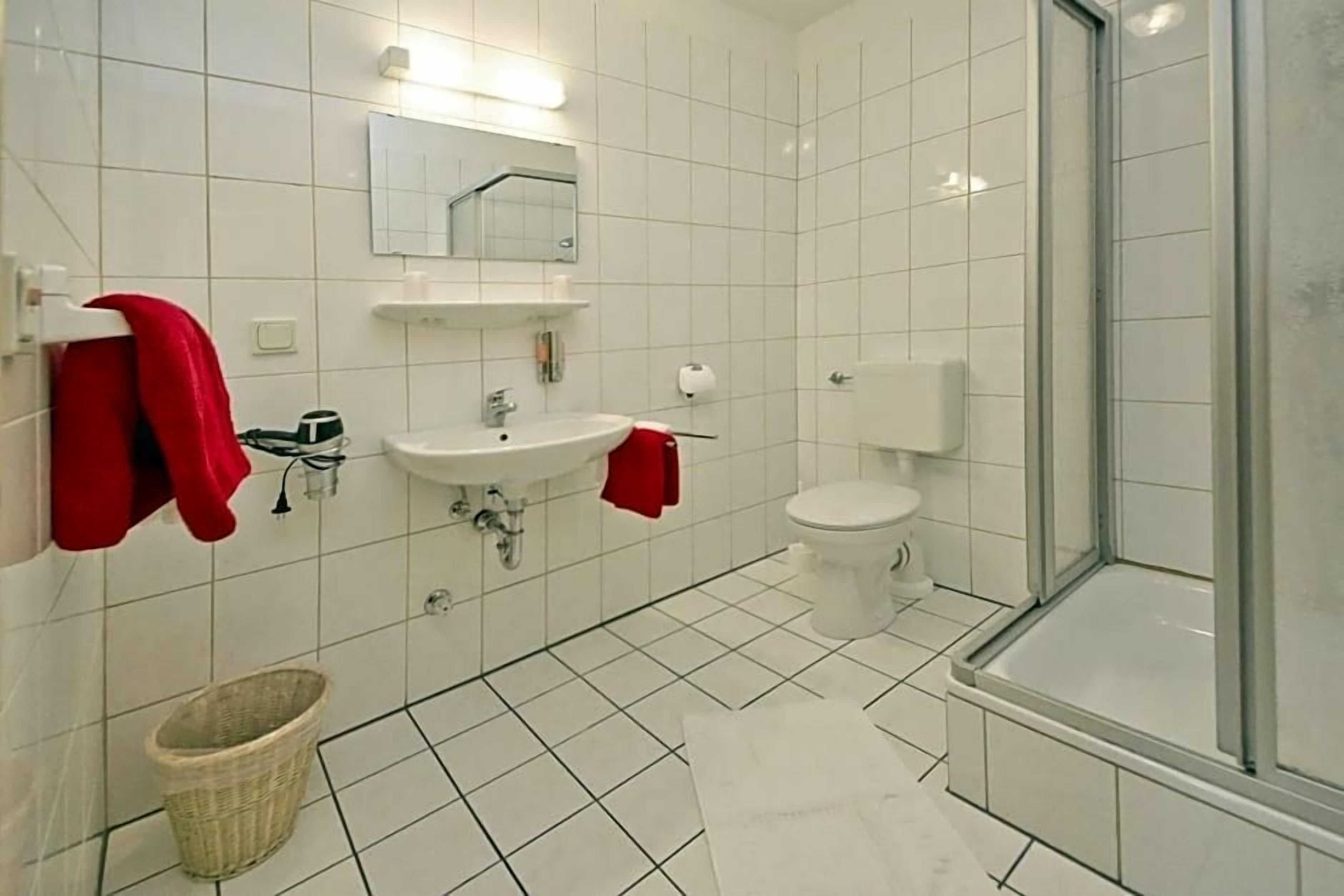 Ein Badezimmer mit weißem Waschbecken, Spiegel, Toilette und Dusche.