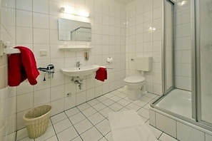 A bathroom with a white sink, mirror, toilet, and shower.
