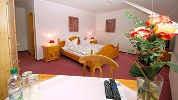 Ein Schlafzimmer mit einem hölzernen Bett, Nachttischen, einem Sessel, einem Tisch mit Blumenvase und einer Fernbedienung.