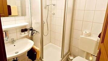 Ein Badezimmer mit Dusche, Toilette, Waschbecken und Spiegel.
