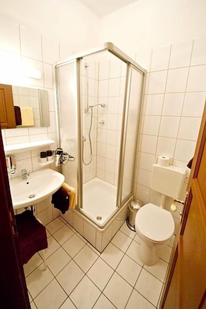 A bathroom with a shower, toilet, sink, and mirror.