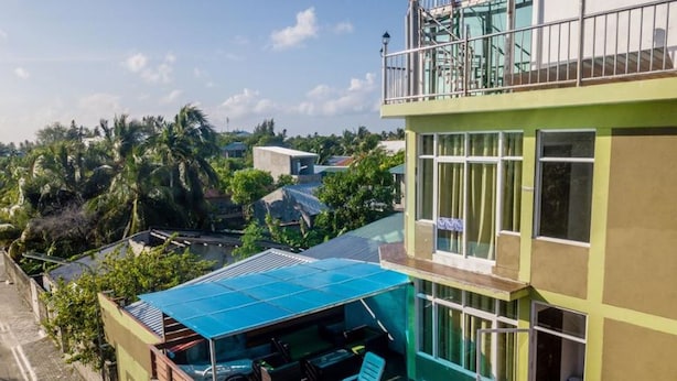 A modern building with a rooftop patio featuring a glass enclosure and lounge chairs. - Sunset Stay Maldives (Thinadhoo)