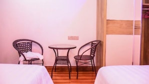 A small room with two beds, a round table, and two wicker chairs. - Sunset Stay Maldives (Thinadhoo)