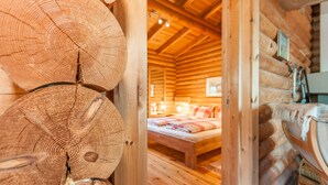 A log cabin interior with a wooden bed and a visible fireplace. - Landgasthof Ropferhof (Telfs)