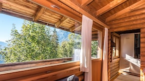 A wooden cabin interior with a large window overlooking a forest and mountains. - Landgasthof Ropferhof (Telfs)