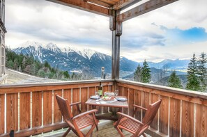 A wooden deck with a table set for two, overlooking a mountainous landscape. - Landgasthof Ropferhof (Telfs)