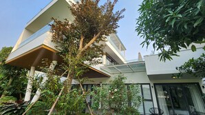 Un bâtiment moderne à deux étages, doté d’une façade en verre, entouré d’une végétation luxuriante et d’un jardin bien entretenu.