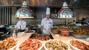 Un buffet proposant une variété de plats, notamment des fruits de mer et des grillades, dans un espace de cuisine professionnelle.