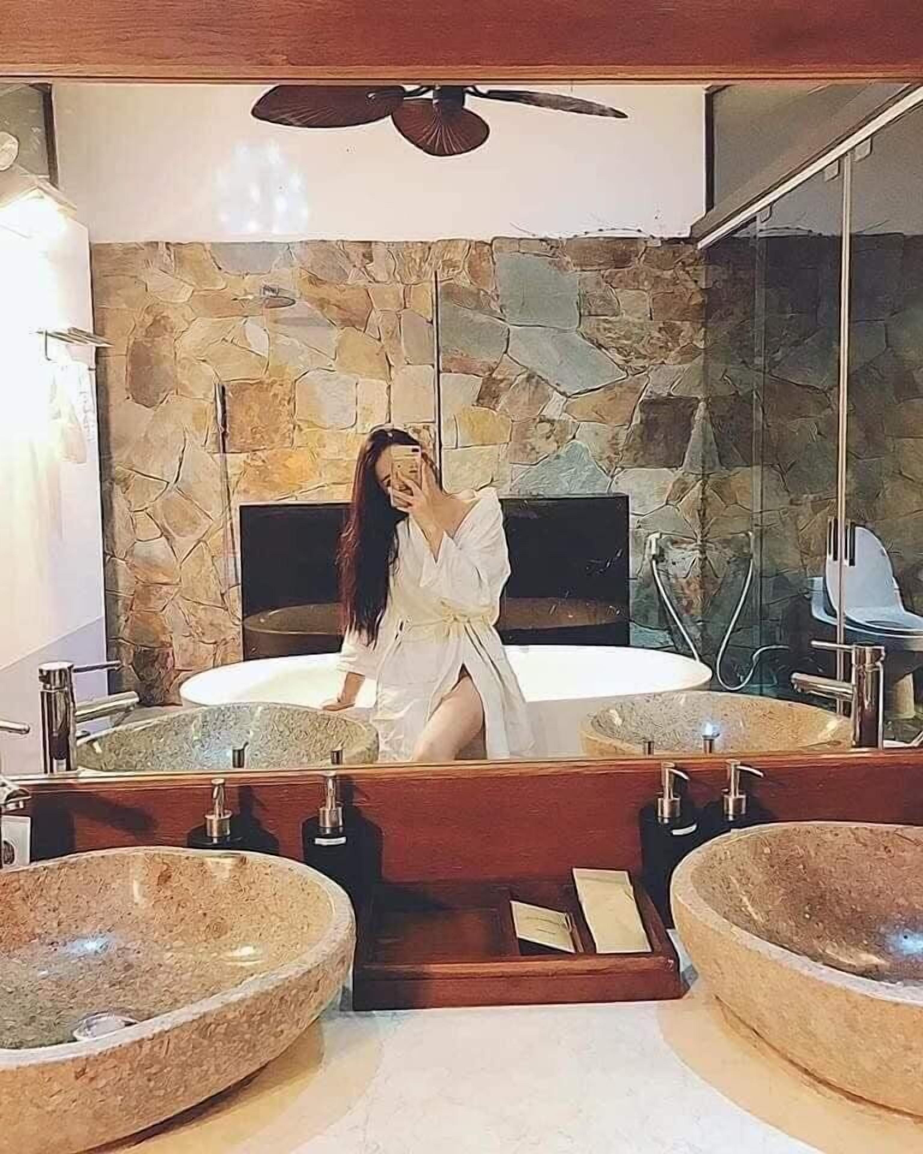A bathroom with a stone wall, two sinks, and a large mirror.