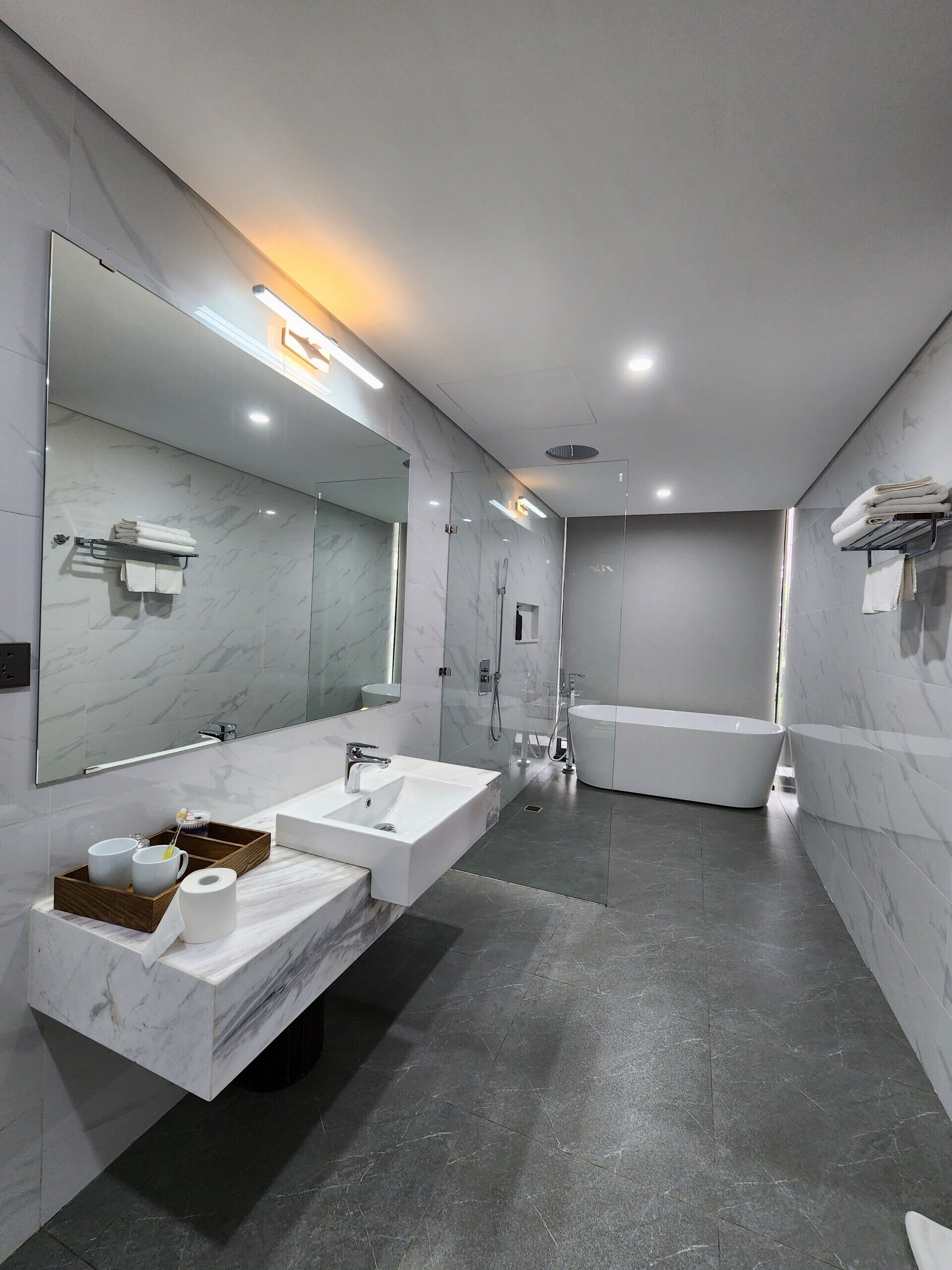 Een moderne badkamer met een grote spiegel, twee wastafels, een bad en een douche.
