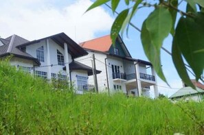 Stylish two-story building with multiple rooms, surrounded by lush greenery.