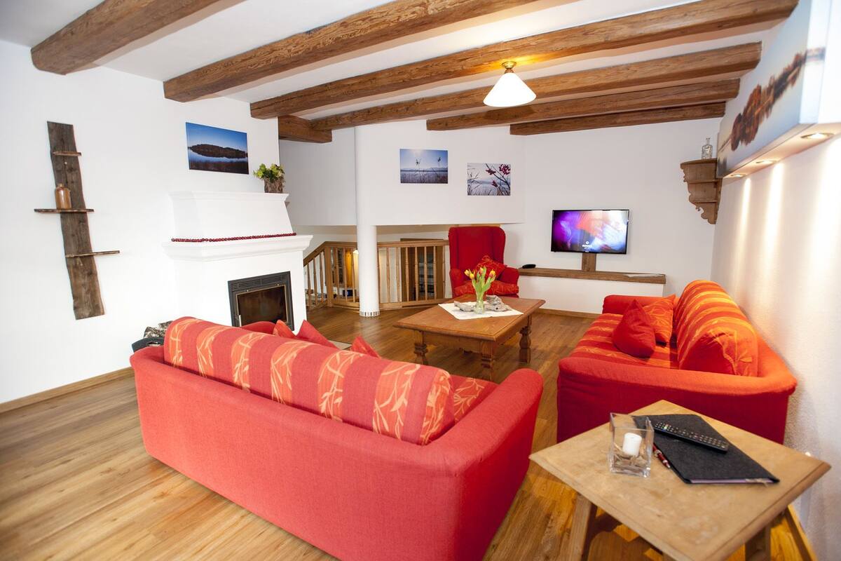 A living room with a fireplace, red sofas, wooden flooring, and a TV.