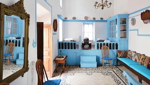 A room with blue walls, a patterned rug, a wooden chair, a blue sofa, and a chandelier. - CasaLindos Theatro (Rhodes)