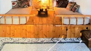 A cozy room with a stone fireplace, wooden benches, and a hanging light fixture. - CasaLindos Theatro (Rhodes)