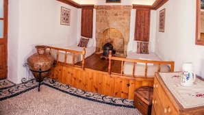 A rustic room with a wooden bed, a stone fireplace, and a wooden ceiling. - CasaLindos Theatro (Rhodes)