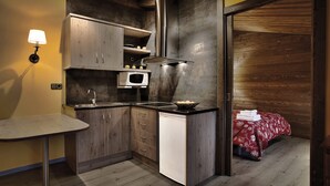 A compact kitchen with a microwave, sink, and wooden cabinets. - Hostal Piteus (Sant Llorenc de Morunys)