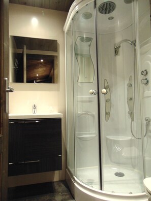 A modern bathroom with a glass-enclosed shower, a sink, and a mirror above the vanity. - Hostal Piteus (Sant Llorenc de Morunys)