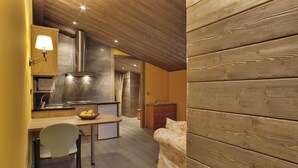 A compact kitchen with a dining area, wooden walls, and a small sofa. - Hostal Piteus (Sant Llorenc de Morunys)