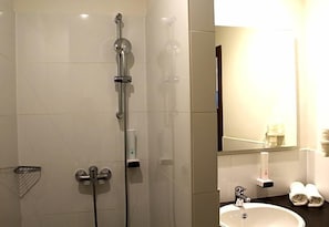 A bathroom with a shower, a sink, and a mirror. - Come In Hotel (Ingolstadt)