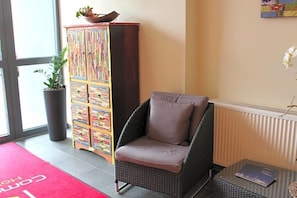 A wicker chair with a cushion, a colorful cabinet, and a red carpet with text.