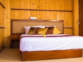 Quarto com painéis de madeira, uma cama, uma mesa de cabeceira e uma tomada na parede.