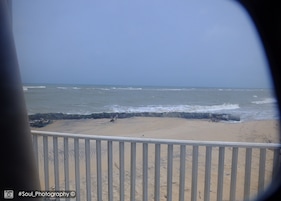 Vista da praia com um corrimão em primeiro plano.